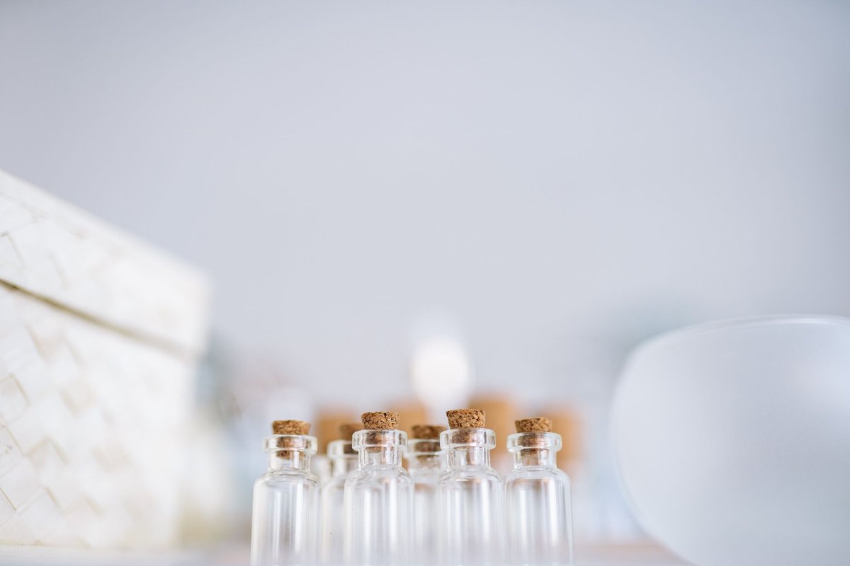 A minimalist close-up of several glass bottles with corks, featuring a blurred background.