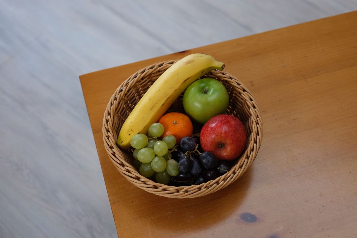 Vibrant assortment of fruits in a woven basket on a wooden tabletop.