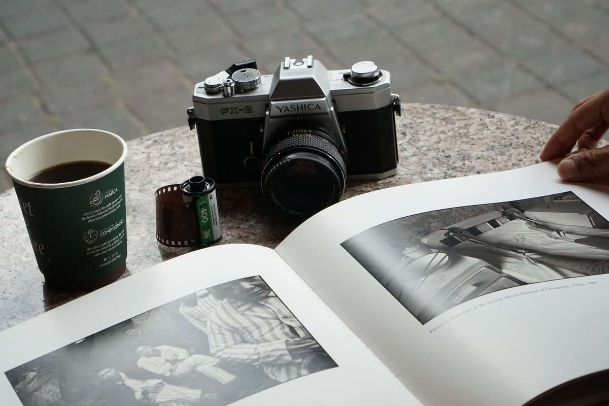 A vintage Yashica camera with a photo book and coffee on an outdoor table.