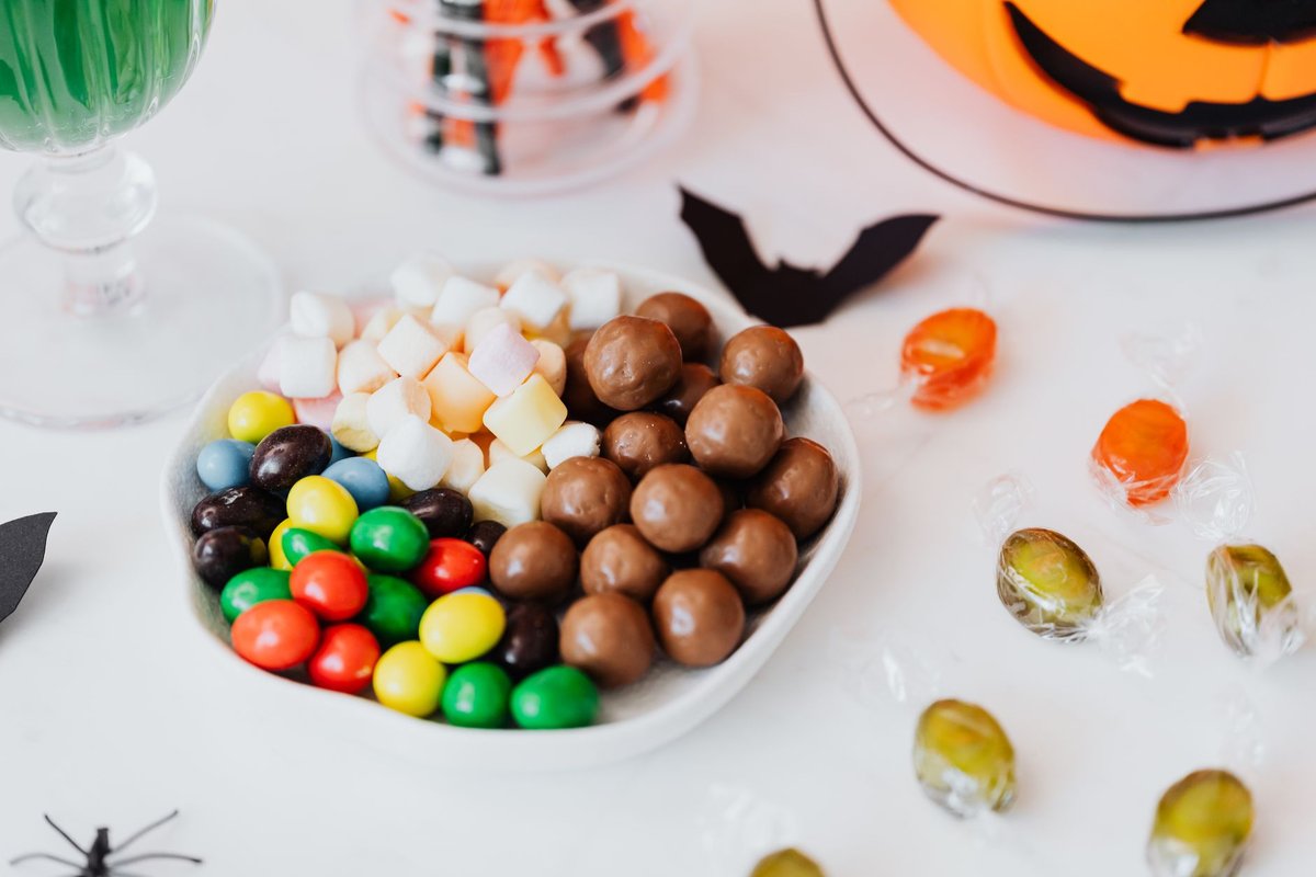 Festive Halloween candy assortment with chocolate, marshmallows, and jack-o'-lantern decor.