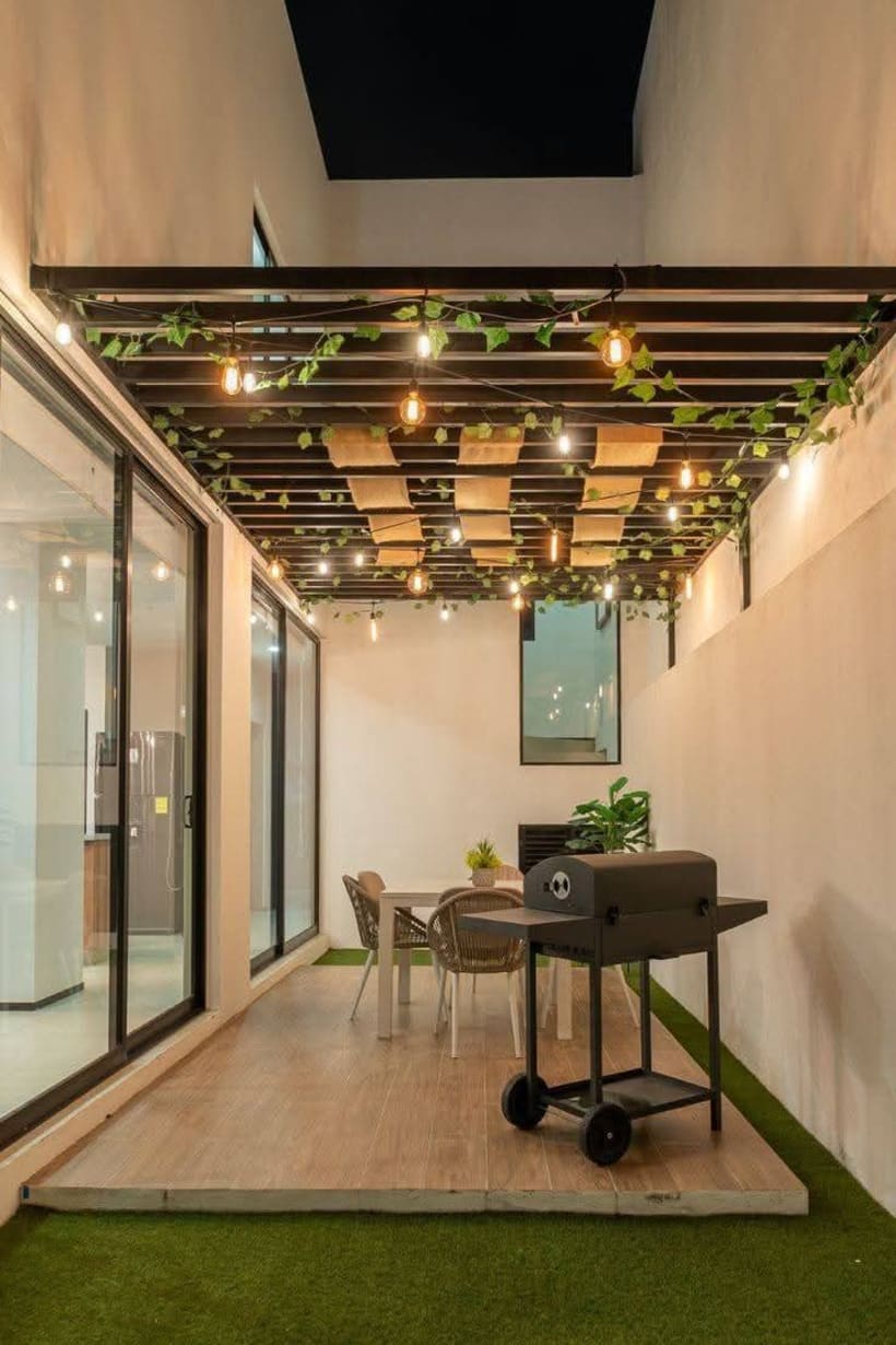 Terraza moderna con parrilla, mesa y luces decorativas