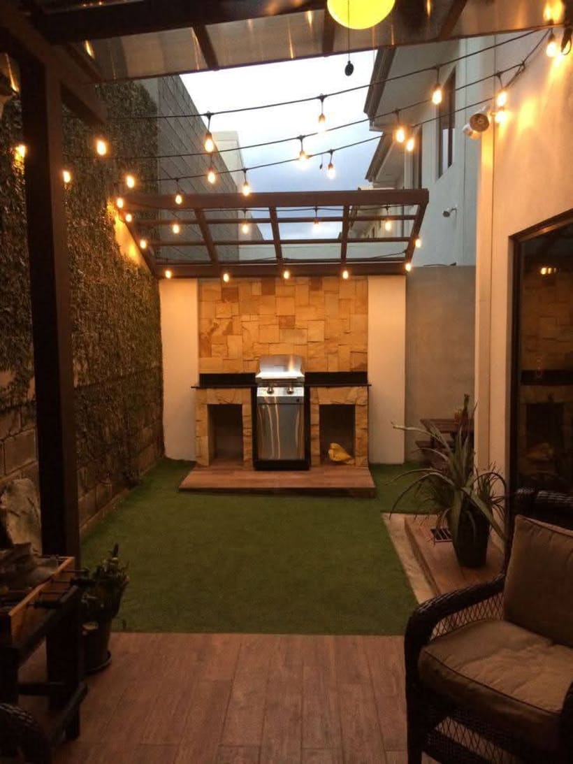 Terraza moderna con parrilla de piedra y luces colgantes