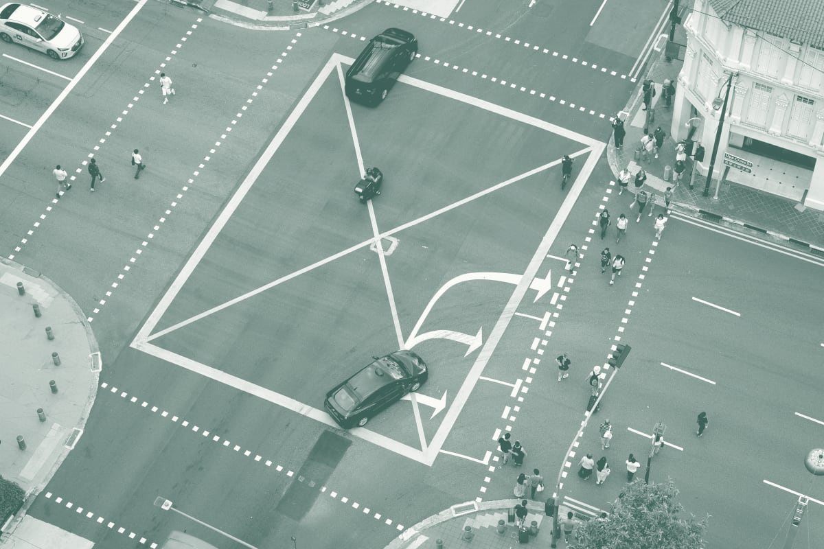 Aerial view of a yellow box junction in Singapore, cars stopped inside the box while pedestrians cross around them