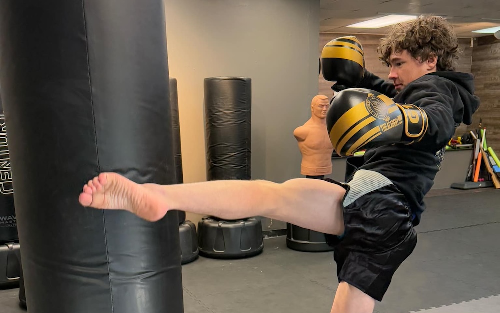 man kicking a heavy bag