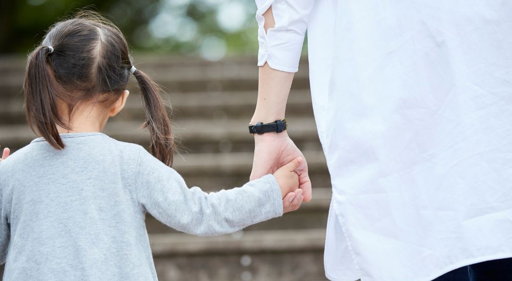 little girl holding the hand of an adult