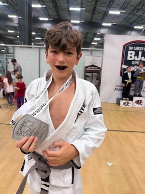 kid in a BJJ gi holding a medal