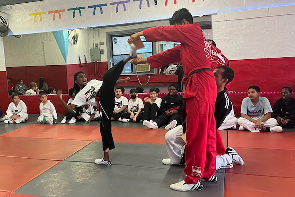 girl kicking a board in a martial arts class