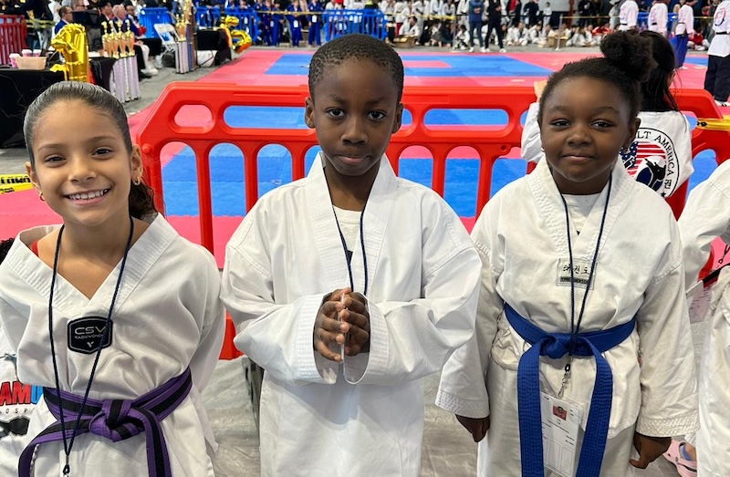 three kids in gis at a martial arts tournament
