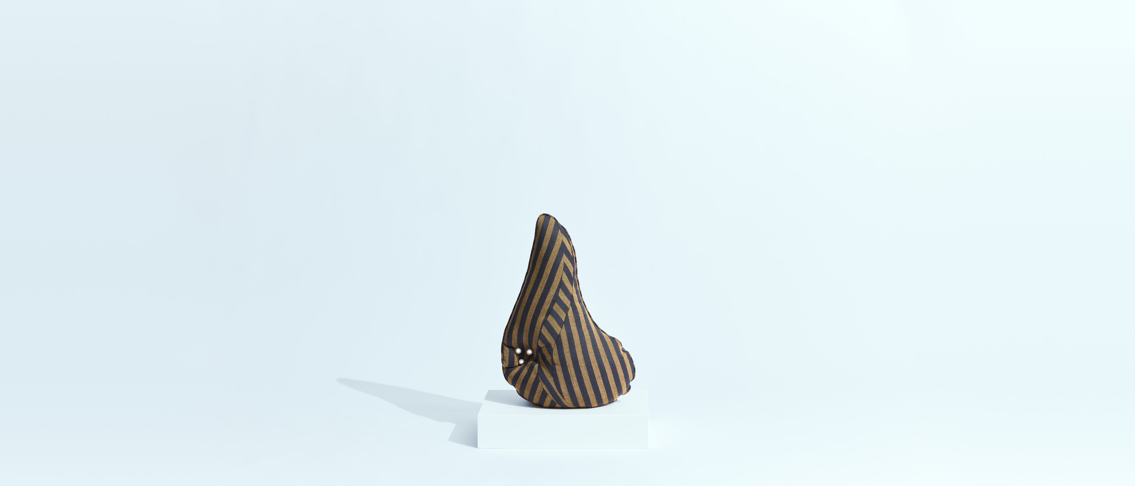 Flora Globe's The Pillow in a brown and black stripe, on a white plinth