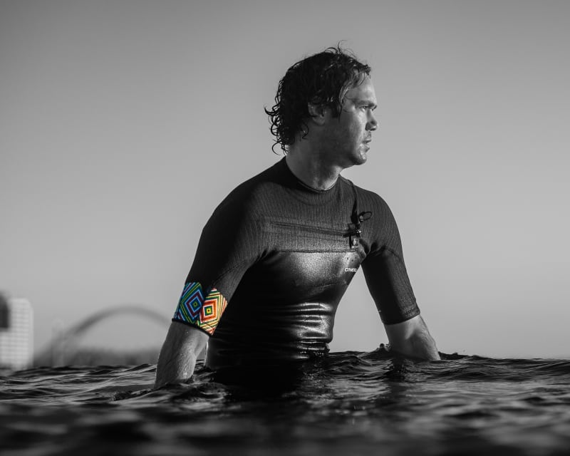 Surfer in an O'Neill wetsuit waist-deep in the ocean, black and white brand photography — Kevin Rom PROFarazzi Media