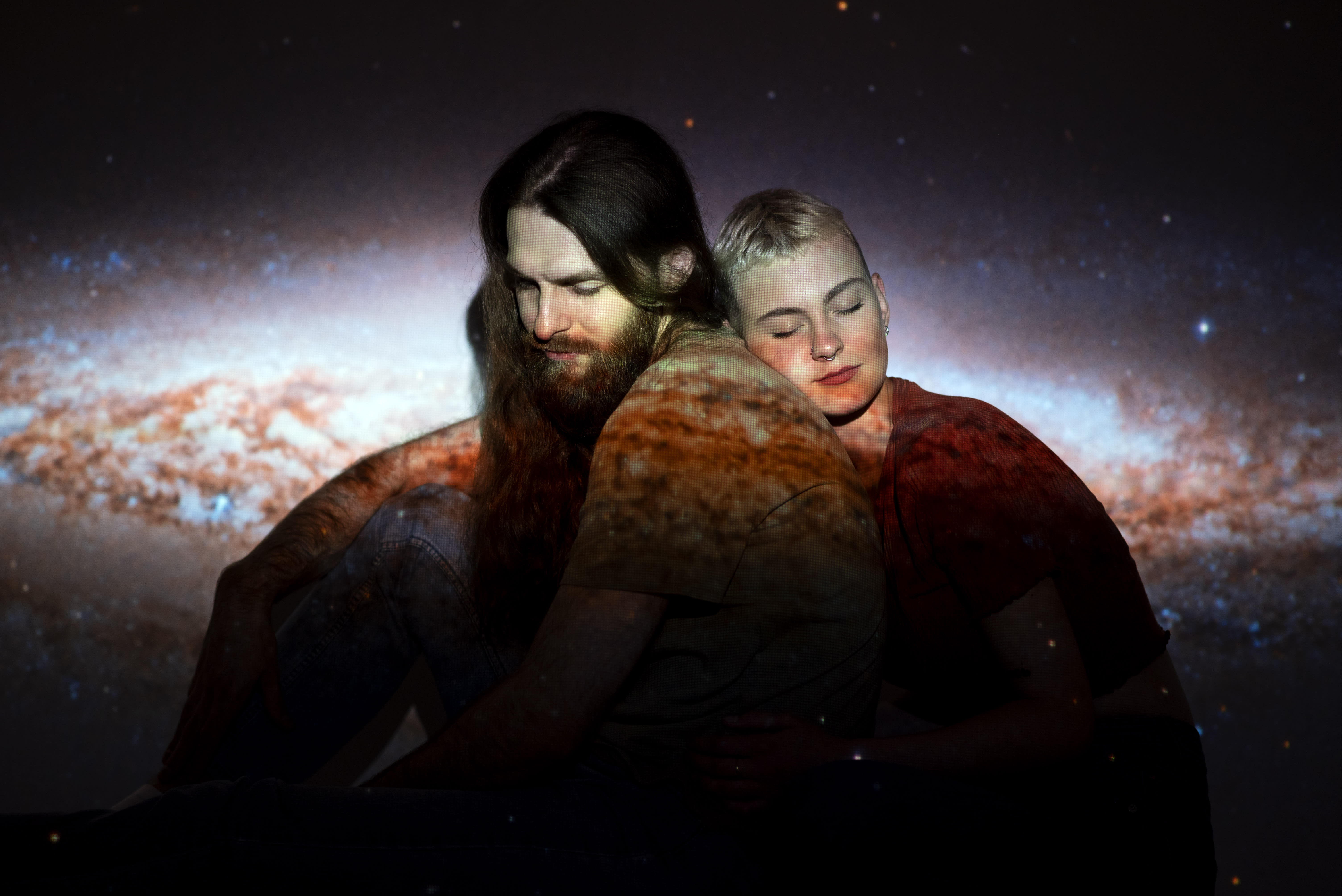 Portrait of and man and woman with the universe projected