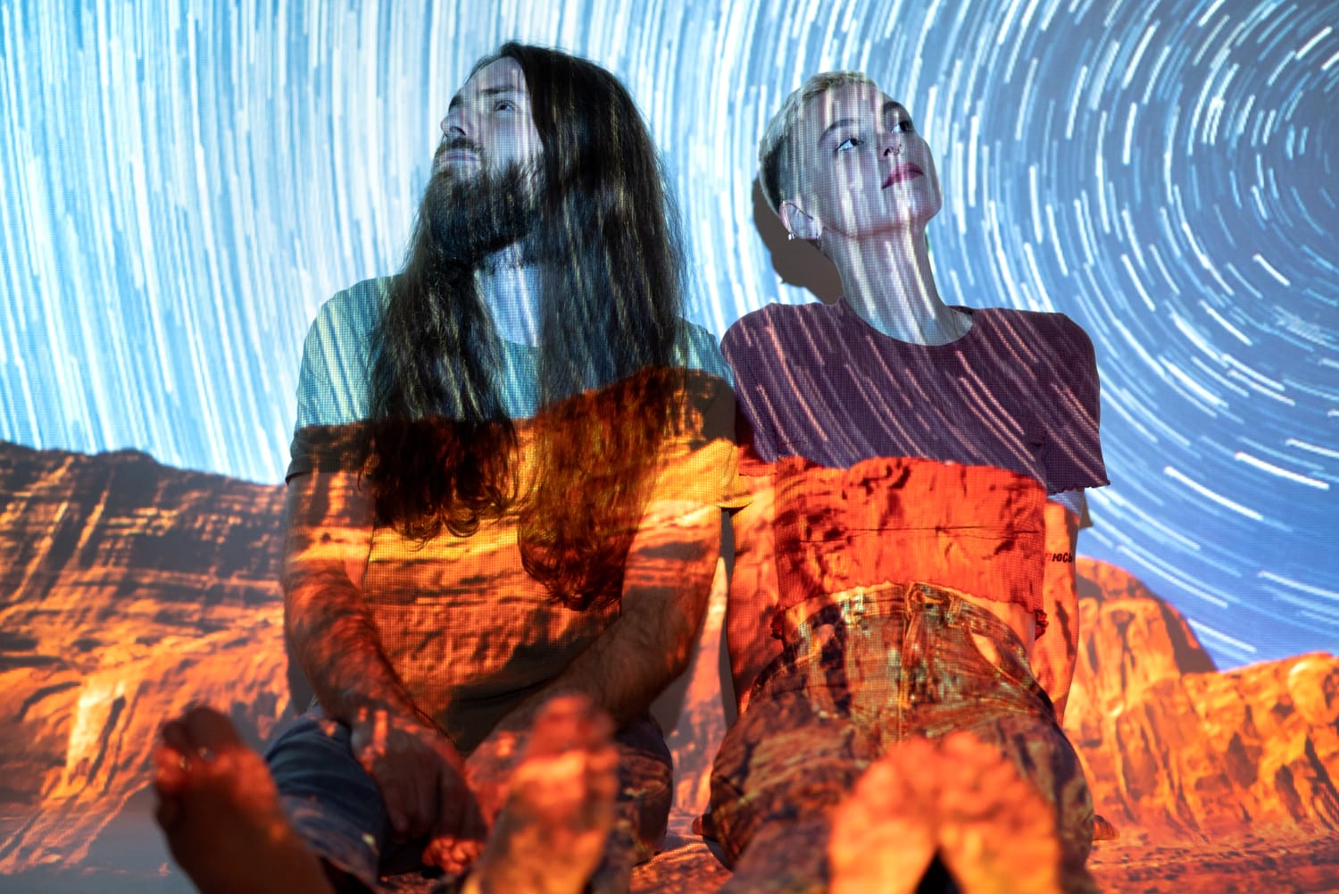 Portrait of a man and woman posing with a projection texture of the universe.