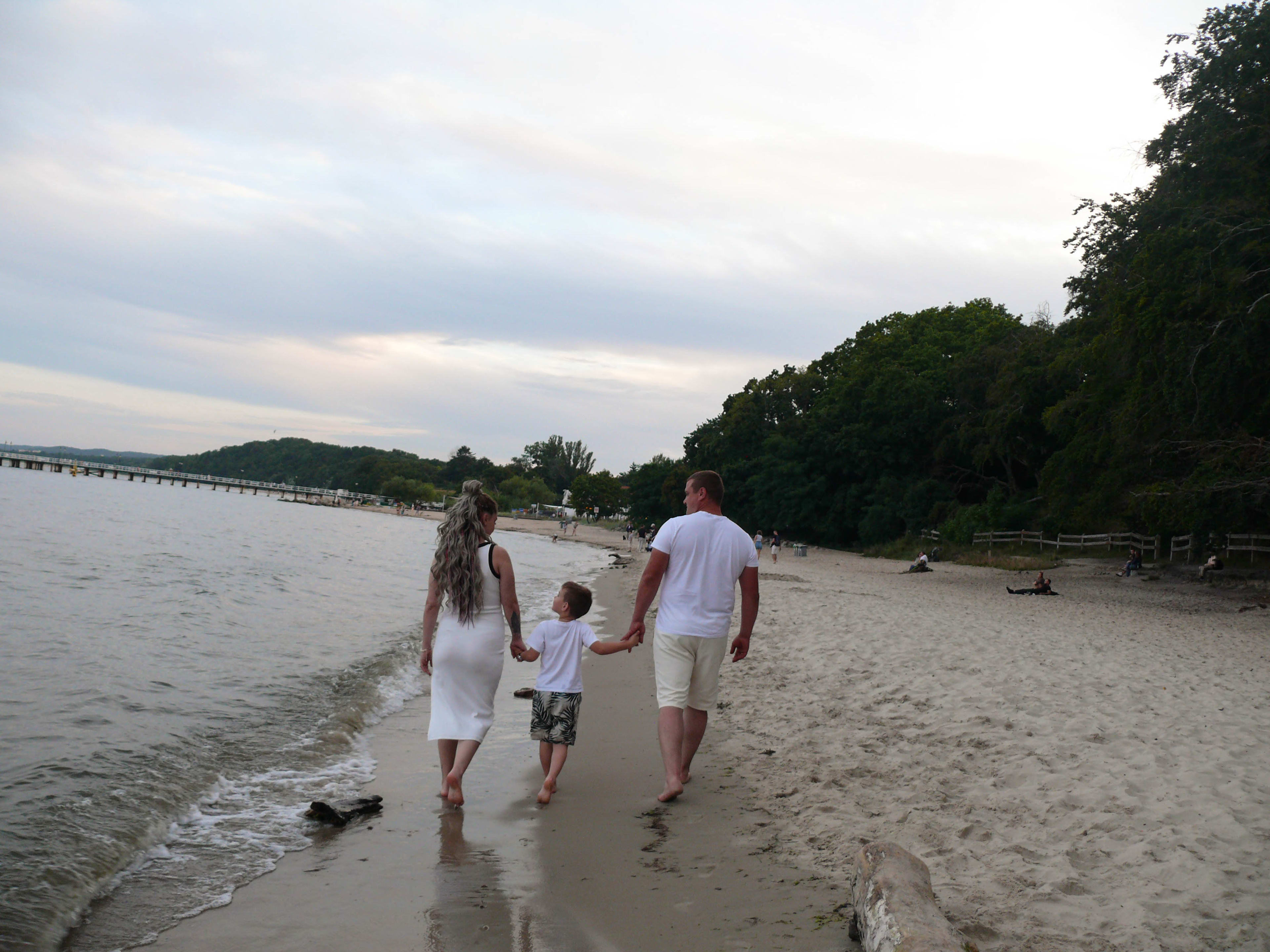 Rodzina na plazy , idaca brzegiem morza , na sesji u fotografa.