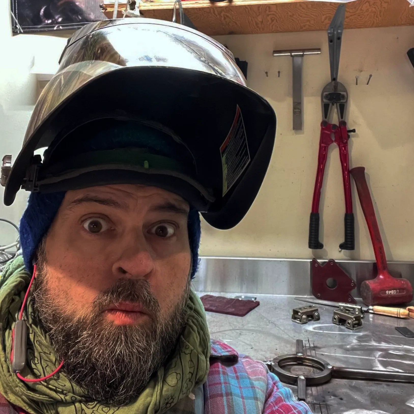 Markoon at his shop with welding visor flipped up, revealing his surprised face