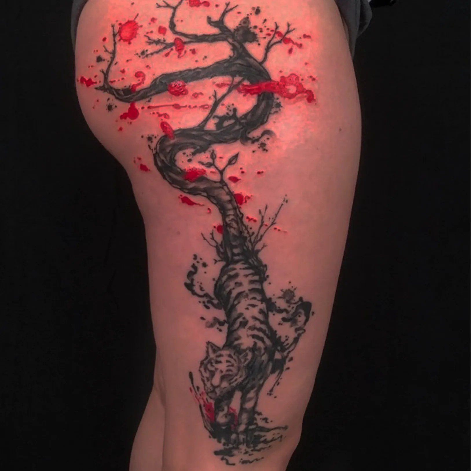 Tattoo by Markoon Dugally; a tiger whose tail is a thick twisting vine, with red and black ink spots