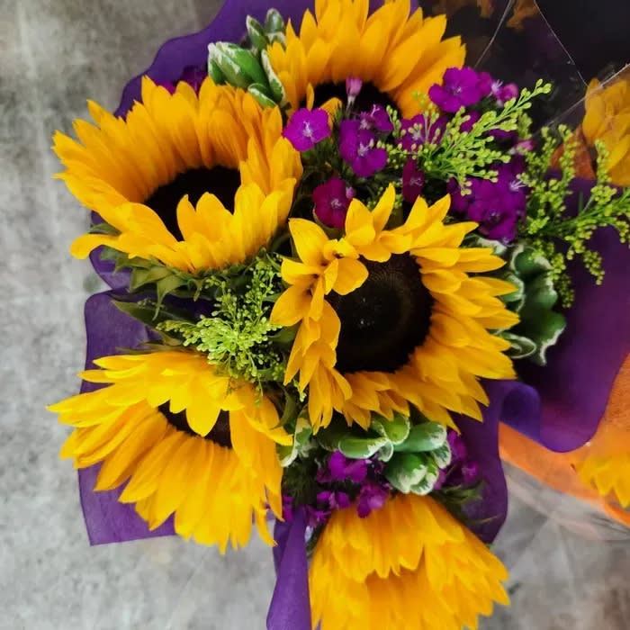 Spring floral wrap (not in a vase)- Sunflower bouquet with asstd greens and flowers.