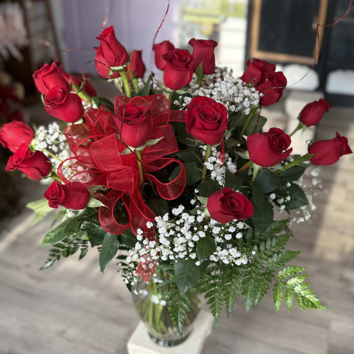 Two dozen roses in a tall vase