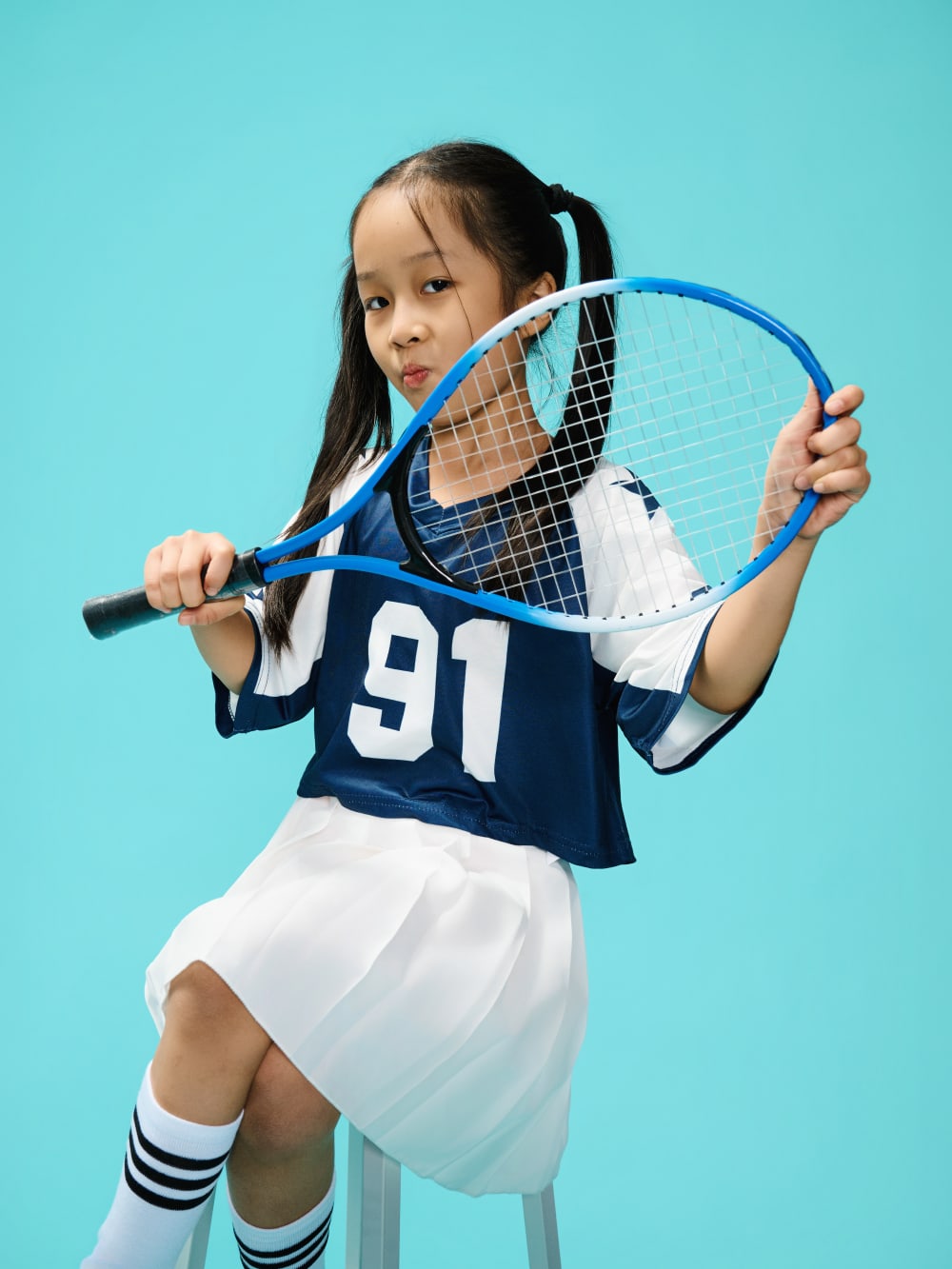 Holding a racket across the face, eyes over the frame, two hands on the grip.
