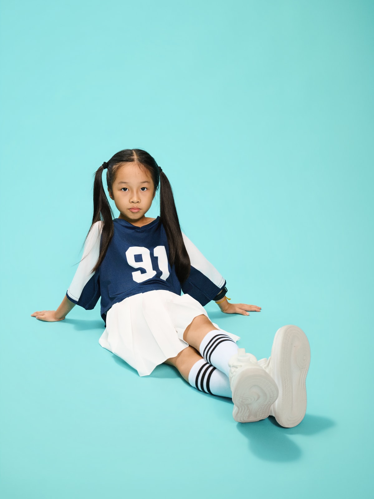 Seated on the floor, leaning back on one arm, full look in view.