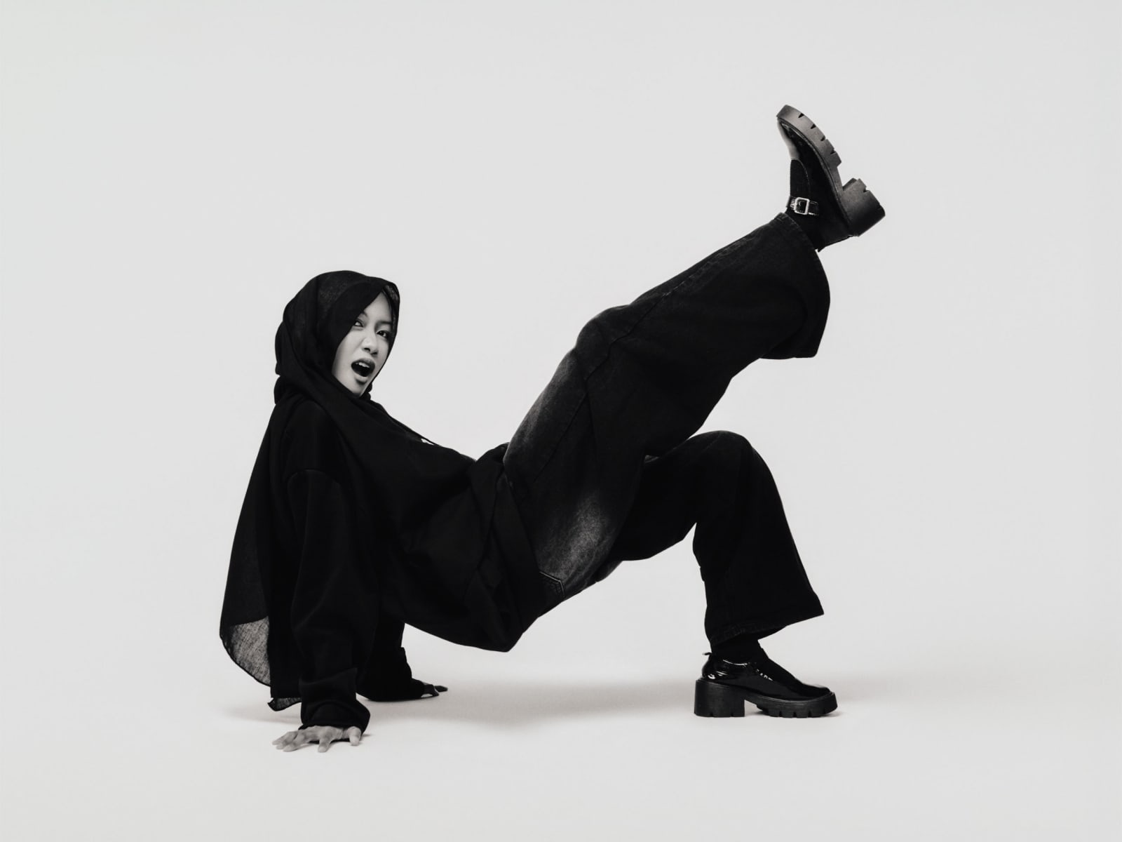 On the floor mid-movement, one booted leg kicked high, mouth open in a shout.