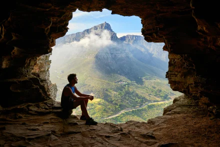 Man Sitting in Cave Overlooking Scenic Landscape