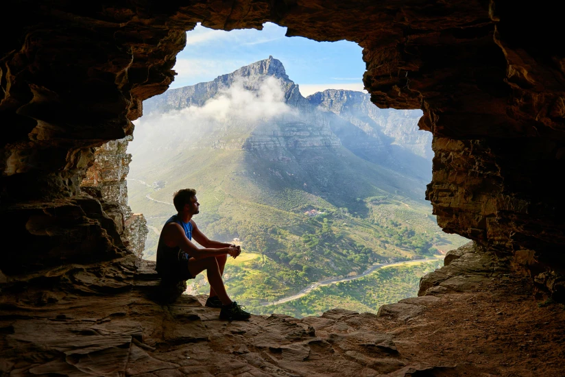 Man Sitting in Cave Overlooking Scenic Landscape