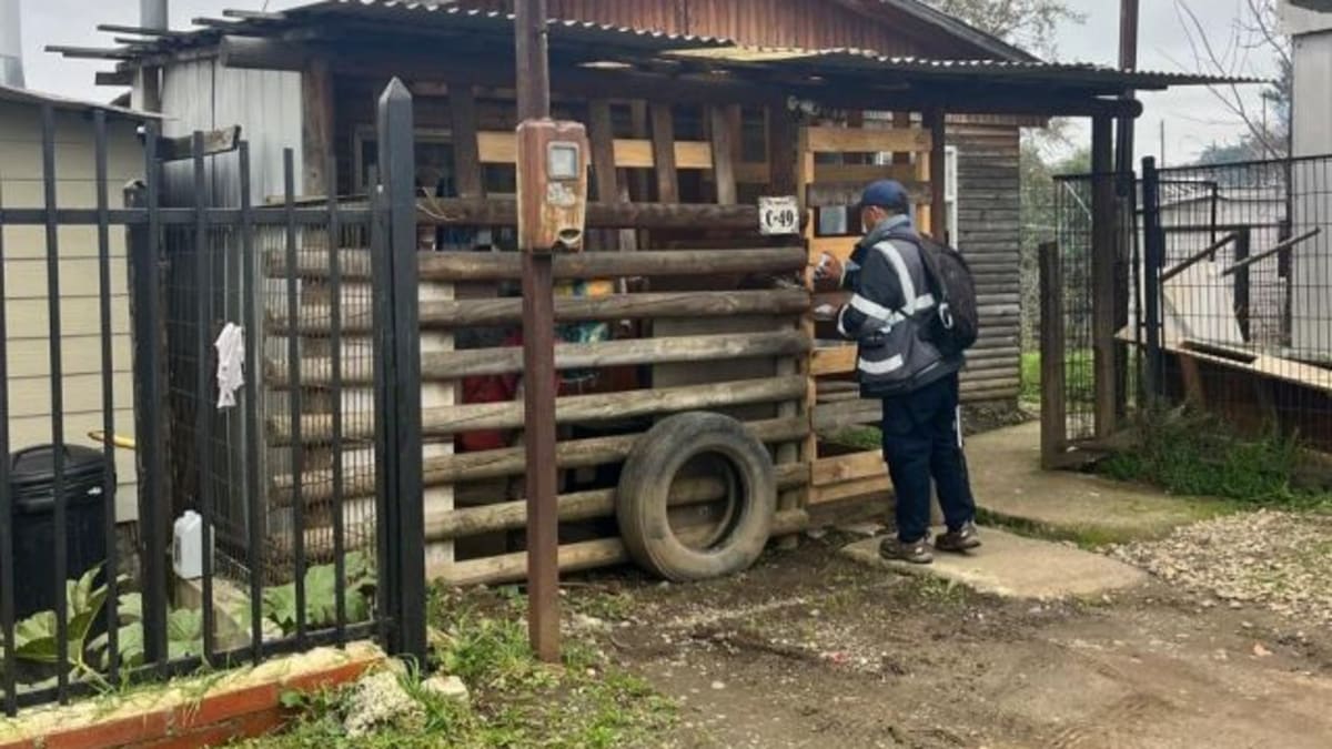 Trabajador en terreno revisa un medidor eléctrico en el acceso de una vivienda