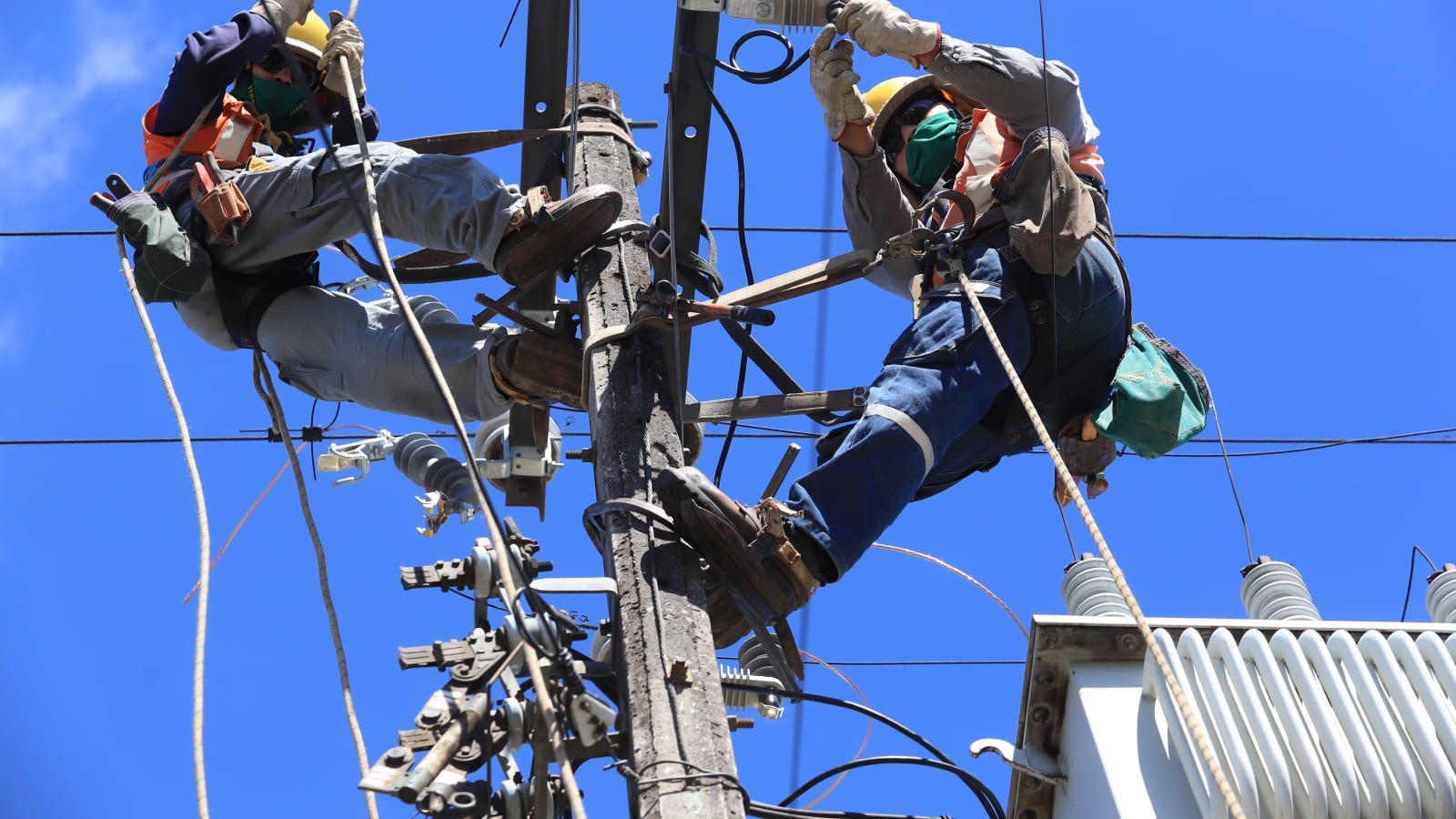 Dos técnicos de Saesa trabajan en altura sobre un poste del tendido eléctrico, imagen de la empresa