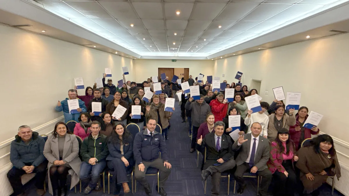 Beneficiarios de la Región de Los Lagos muestran sus certificados de subsidio de tierras junto a autoridades durante la ceremonia de entrega de CONADI en Puerto Montt.