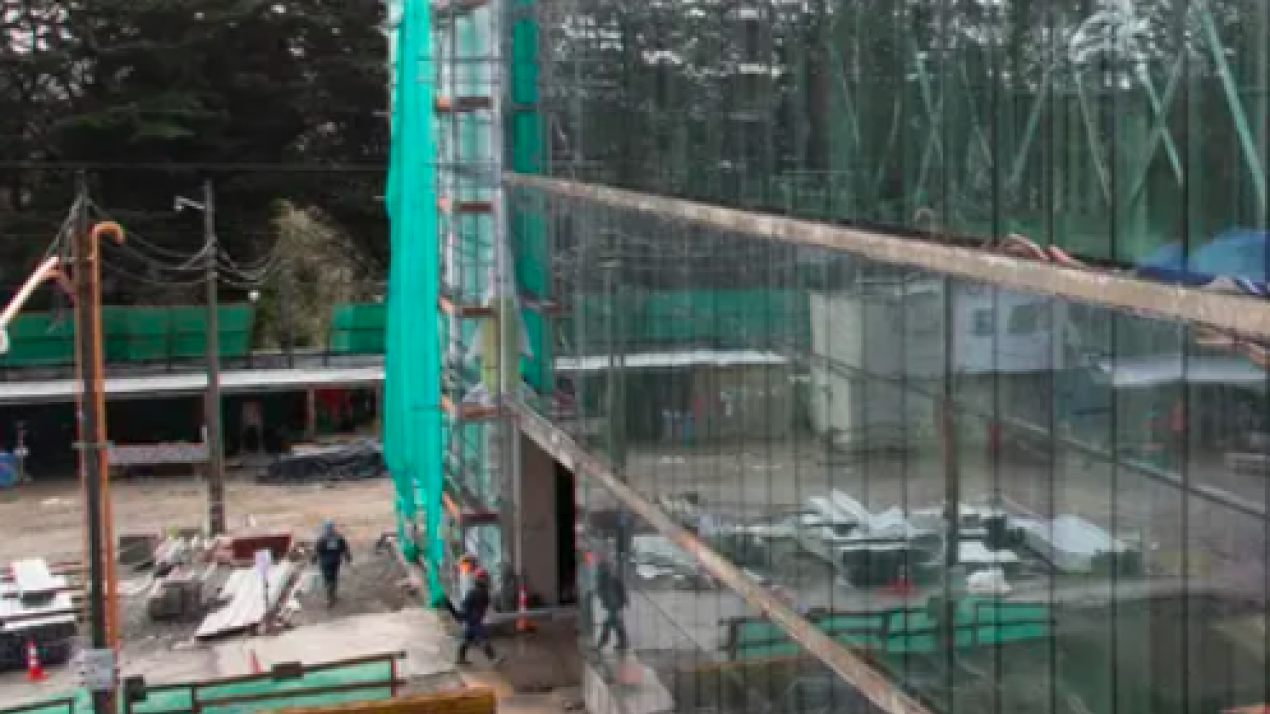 Obras del nuevo Hospital de Puerto Varas, con andamios, malla verde y trabajadores en el terreno
