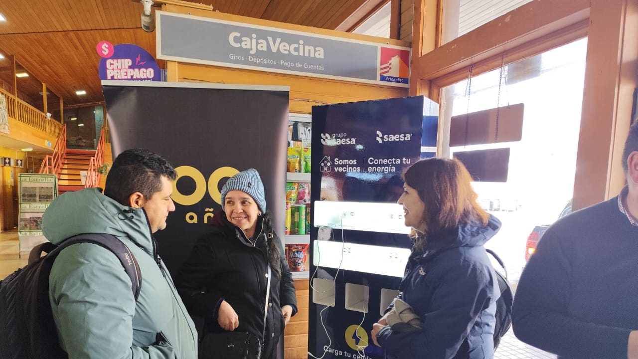 Personas cargan sus teléfonos en un tótem gratuito del programa Conecta tu Energía instalado en un terminal de buses