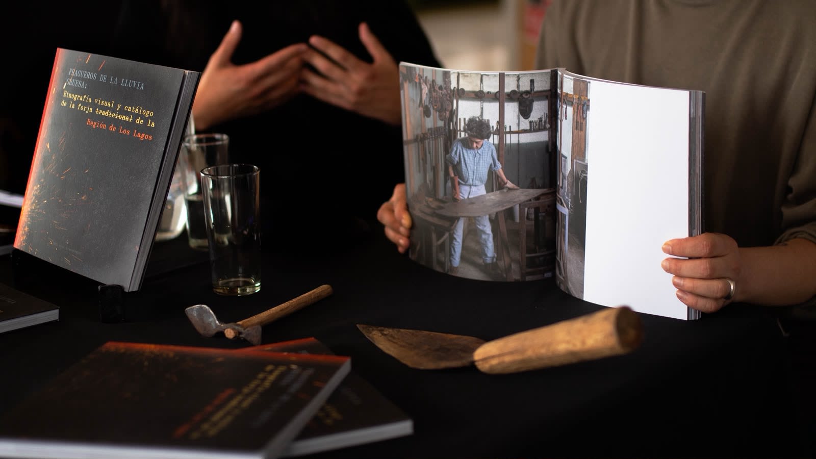 El libro Fragueros de la lluvia gruesa junto a herramientas de forja sobre la mesa de presentación en Puerto Montt
