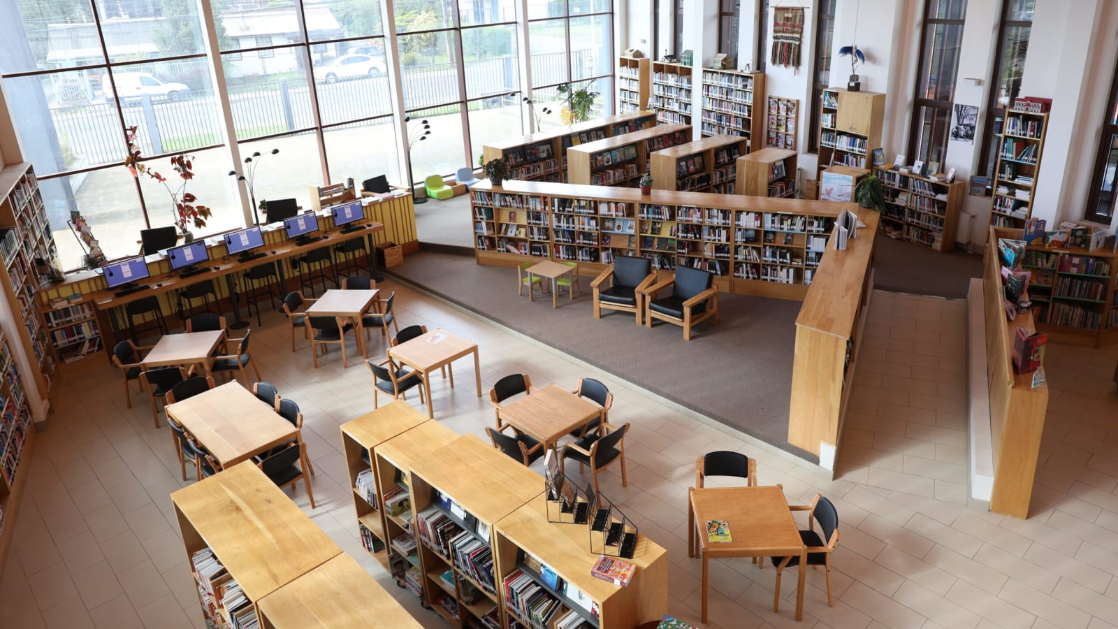 Sala de lectura de la Biblioteca Municipal de Frutillar, con estanterías, mesas y ventanales