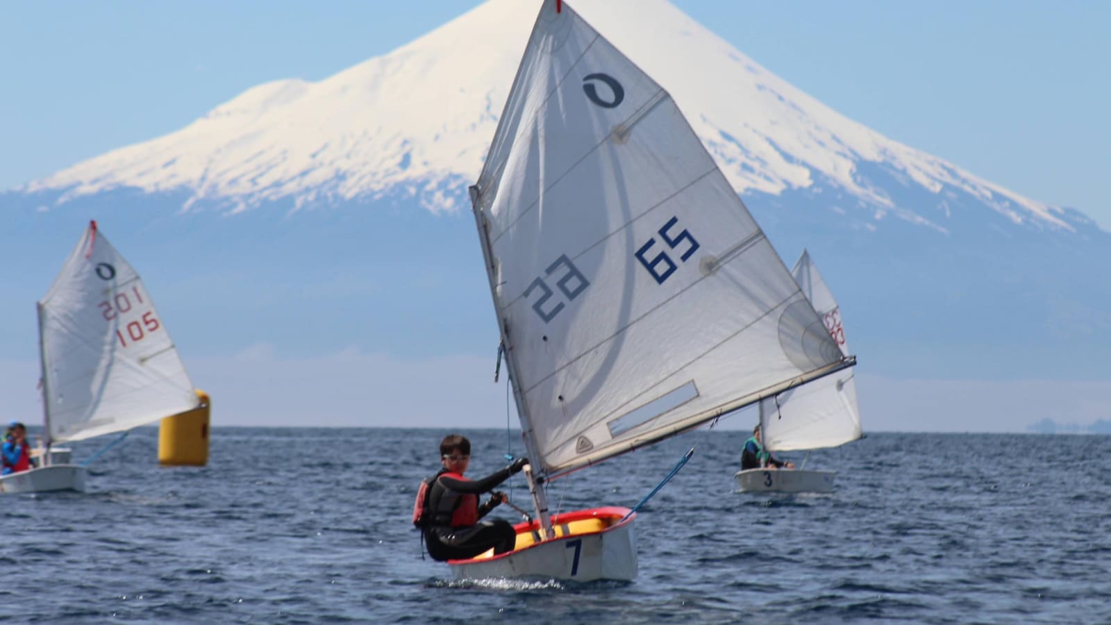 Veleros Optimist navegando en el lago Llanquihue con el volcán Osorno nevado al fondo
