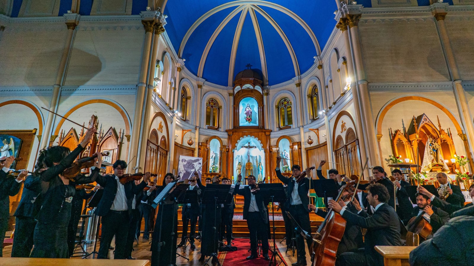 Los músicos de la Orquesta de Cámara de Puerto Montt tocando bajo la cúpula azul de una iglesia