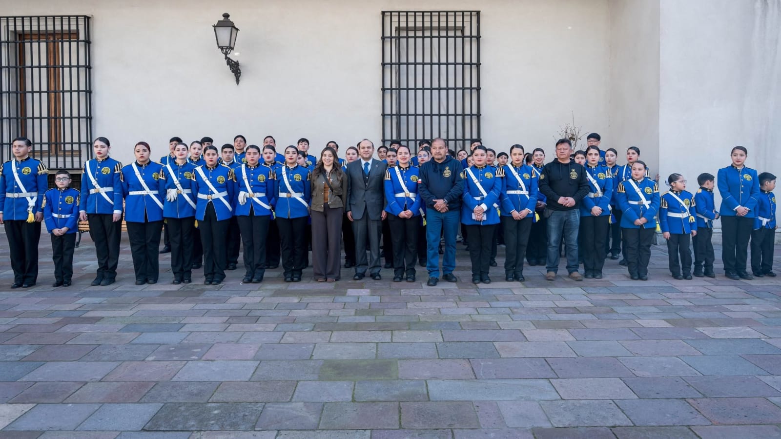 Integrantes de la Banda Escolar Dalcahue, con uniforme azul y bandas blancas, formados en un patio del Palacio de La Moneda