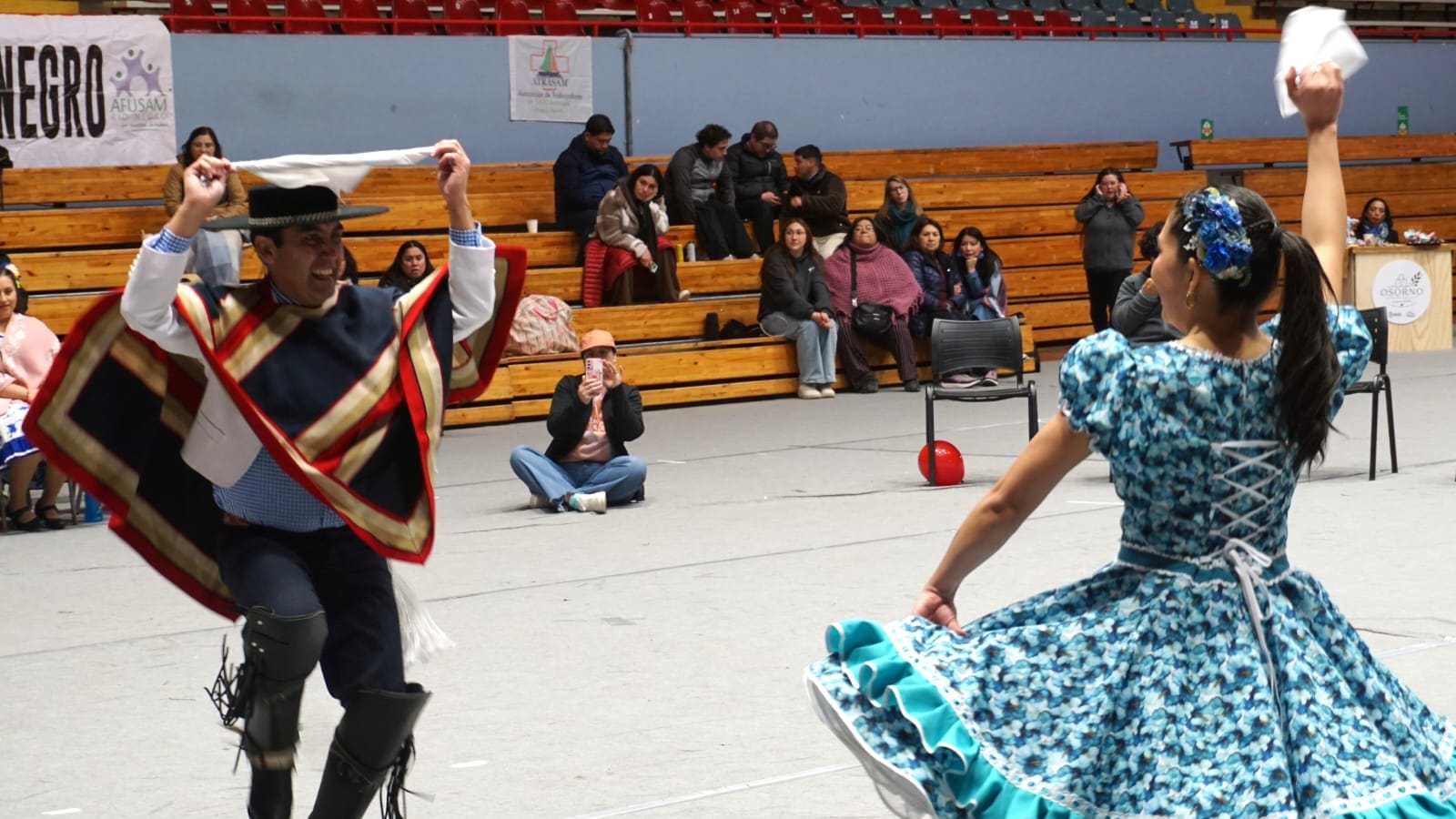 Una pareja baila cueca con pañuelos en alto en el gimnasio María Gallardo de Osorno, durante el campeonato regional de Confusam