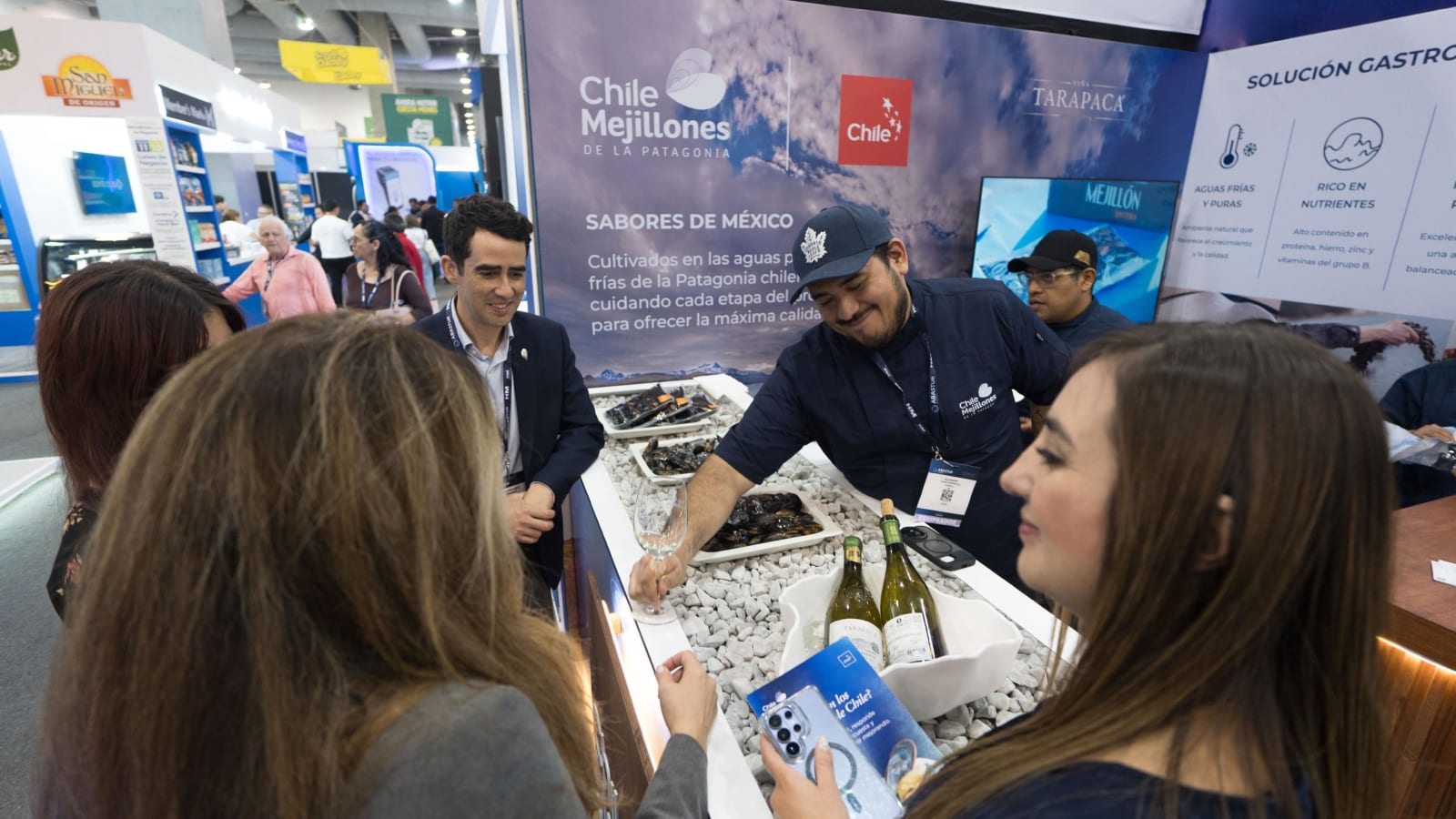 Un cocinero sirve mejillones chilenos a visitantes en el stand de Chile Mussel from Patagonia en la feria ABASTUR de México