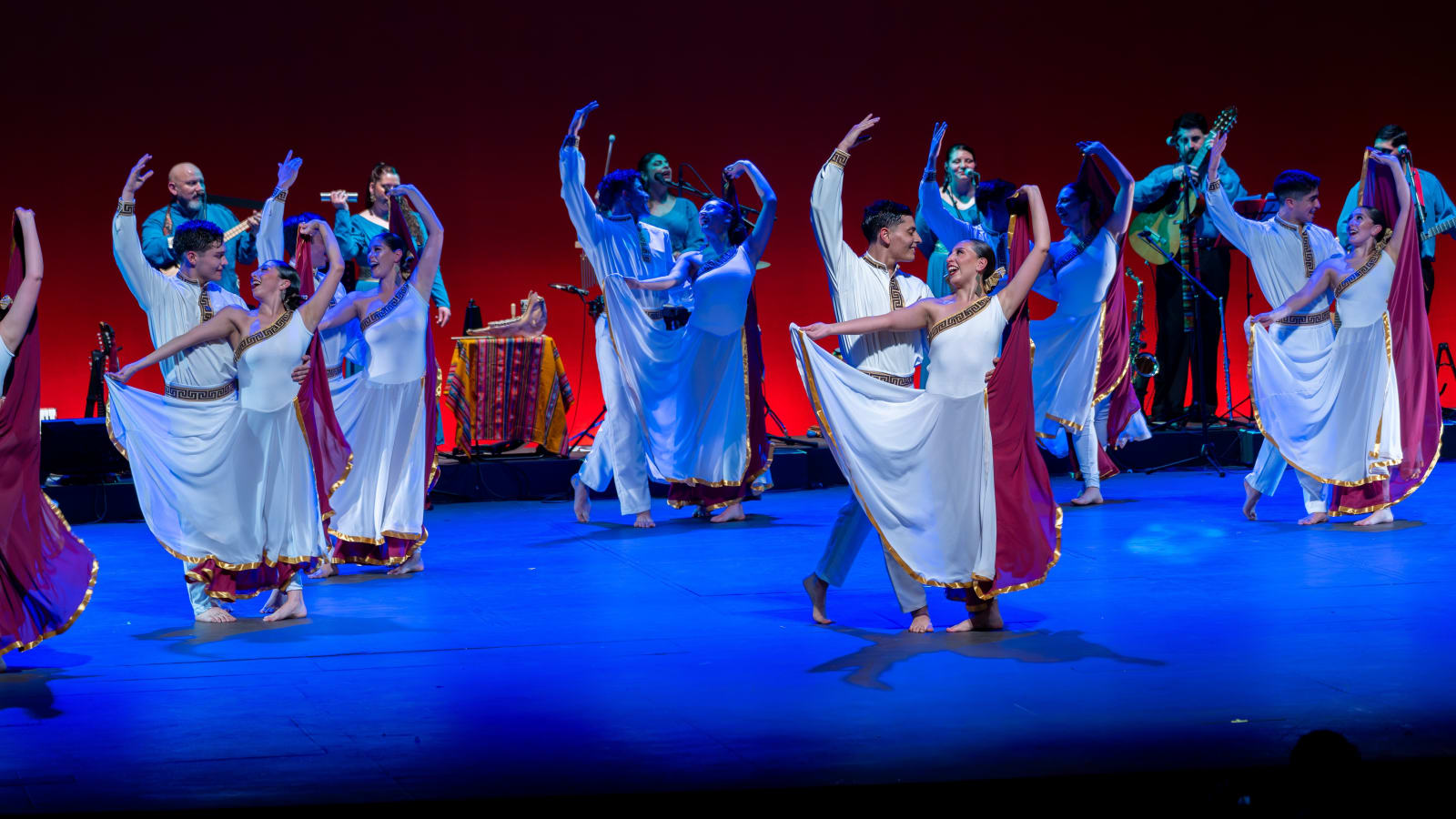 Bailarines del Ballet Folklórico Tupa Marka con vestuario blanco y burdeo durante la función aniversario en el Teatro del Lago