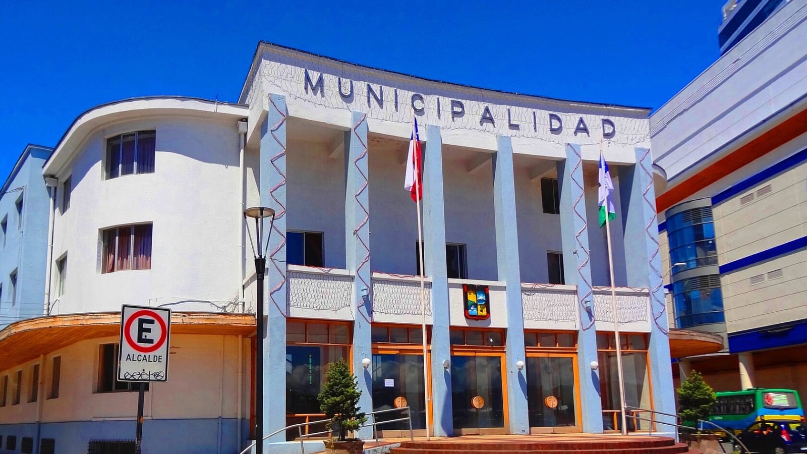 Fachada del edificio de la Municipalidad de Puerto Montt, con sus columnas celestes y las banderas de Chile y de la ciudad