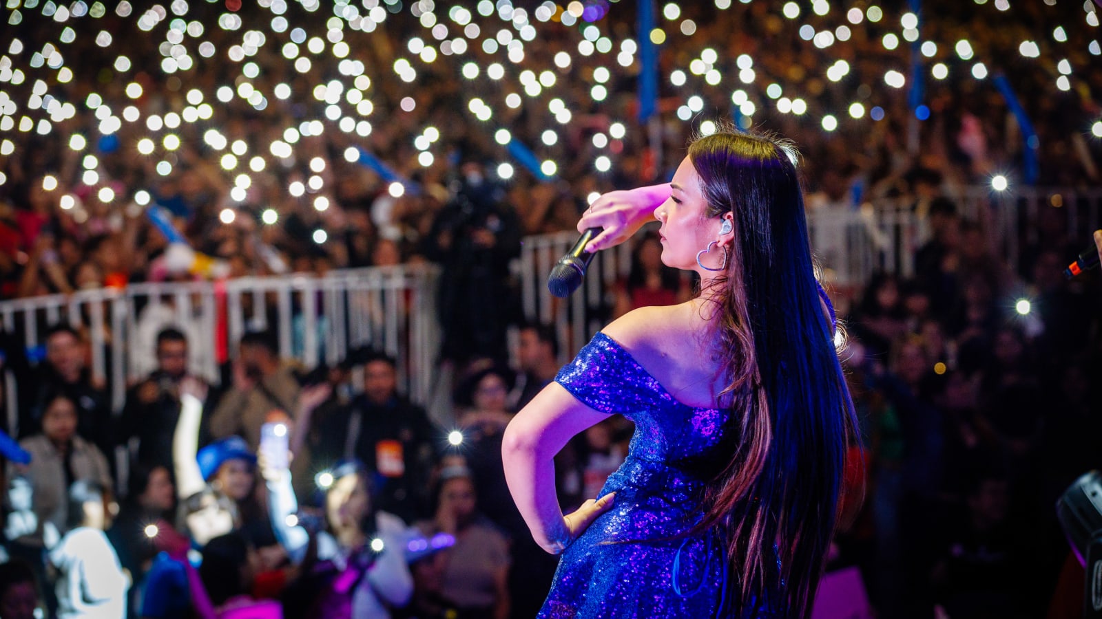 Una cantante en el escenario de la Gira Teletón 2026 frente a un público que ilumina la noche con las linternas de sus celulares