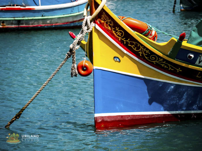 A traditional luzzu boat with an intricate painted design and the protective eyes on its bow, known locally as l-għajnejn