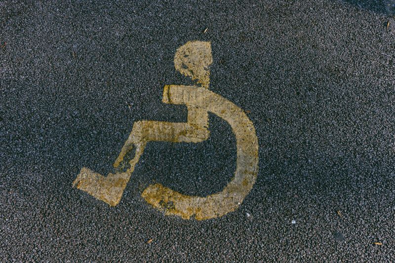Faded yellow wheelchair-accessible symbol painted on dark pavement