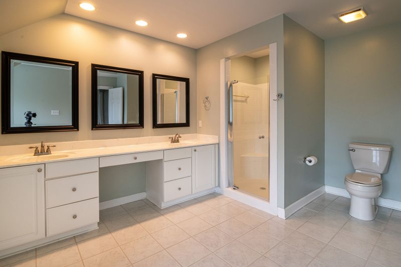 Modern bathroom with white vanity, three mirrors, tiled floor, shower, and toilet