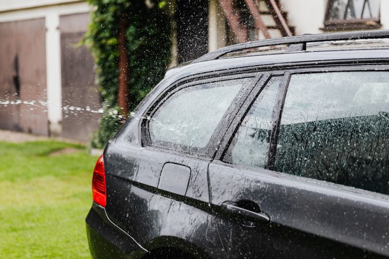 Black SUV parked in heavy rain near a house and garage