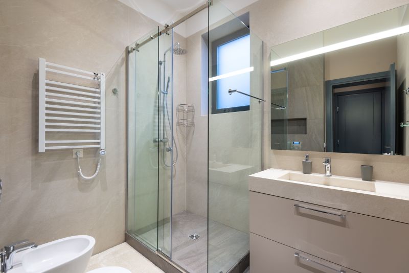 Modern bathroom with glass shower, towel warmer, vanity sink, and large mirror.