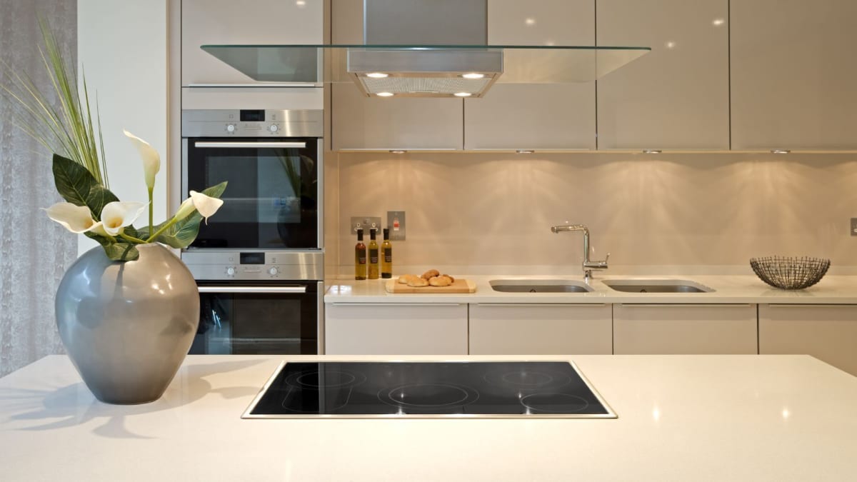 Modern white kitchen with island and flowers. Stainless steel appliances and cabinets.