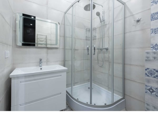 Bathroom with white vanity, glass shower, and tiled walls.