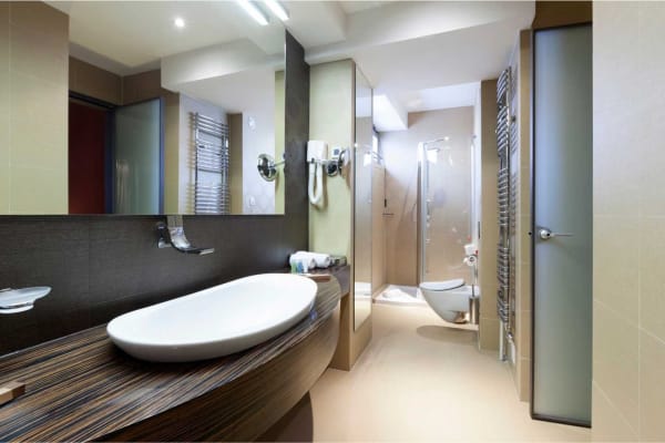 Modern bathroom with a white sink, large mirror, and glass shower.