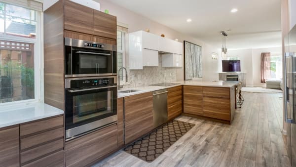 Modern kitchen with wooden cabinets, stainless steel appliances, and white countertops.